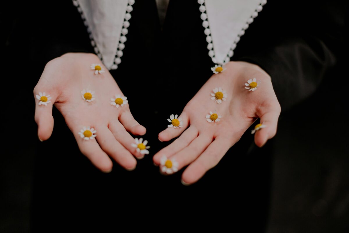 Kädet joissa on kukkia.